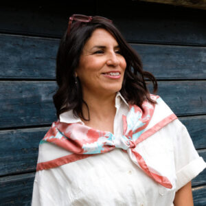 Woman wearing Fresh Beauty large silk square scarf tied over shoulders