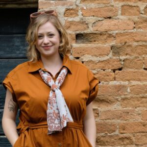 Woman wearing Fern Sprays long silk scarf in Russet and Cool Blue colour under collar of shirt dress